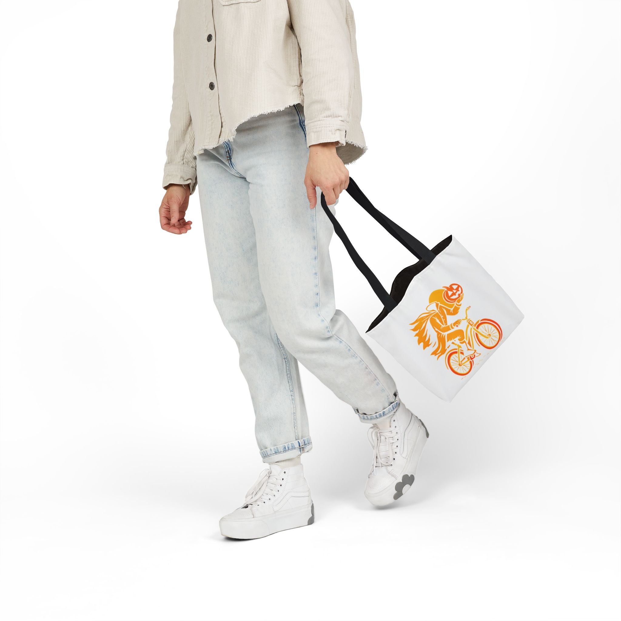 White canvas tote bag with black handles, orange ghost rider pumpkin head on bicycle