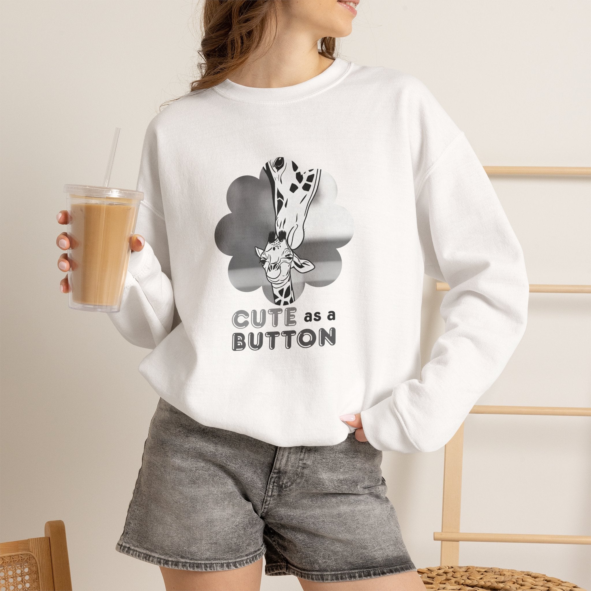 White crewneck sweatshirt with giraffe cloud graphic and "CUTE as a BUTTON" text