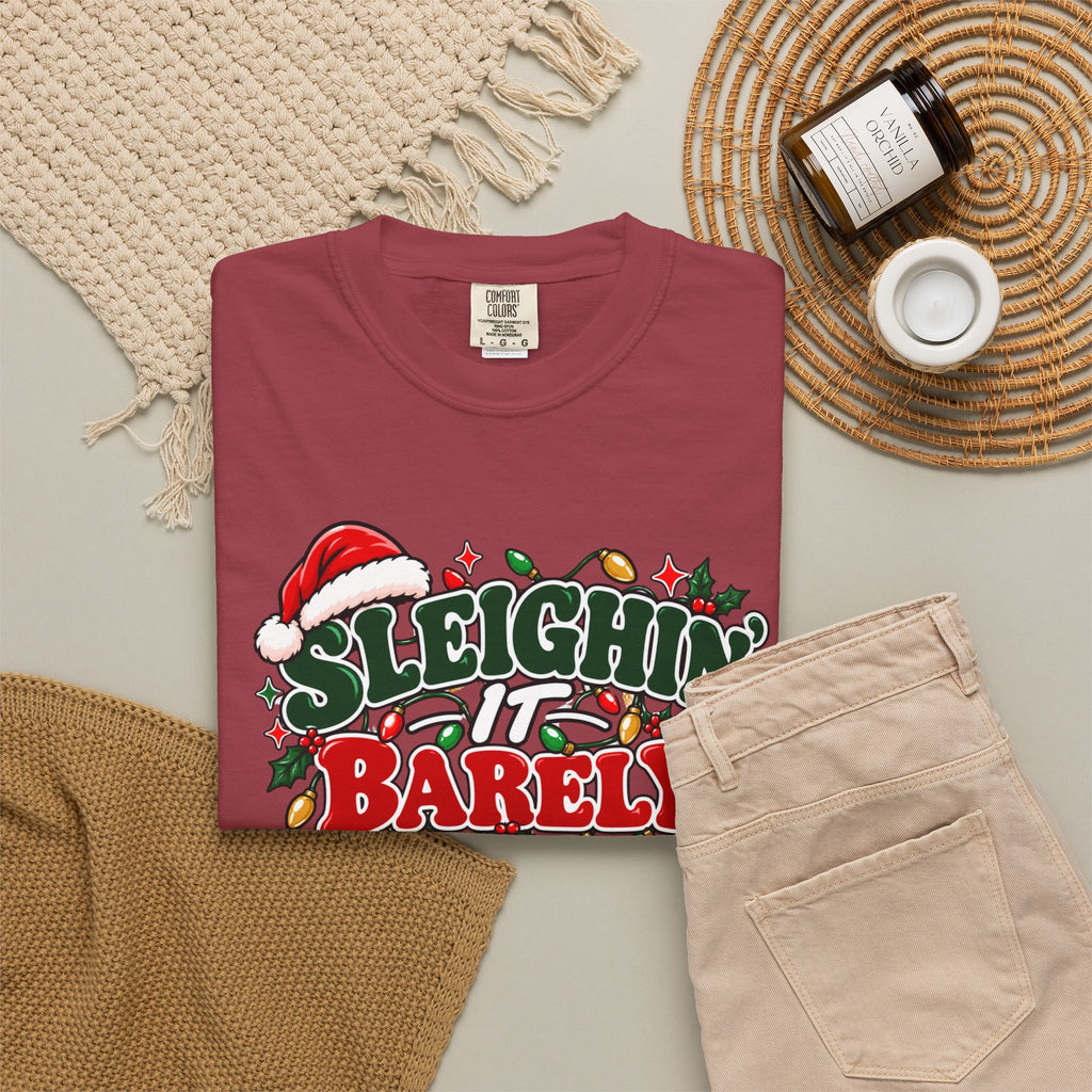 Burgundy crewneck t-shirt with "Sleighin' It Barely" holiday graphic, flat lay
