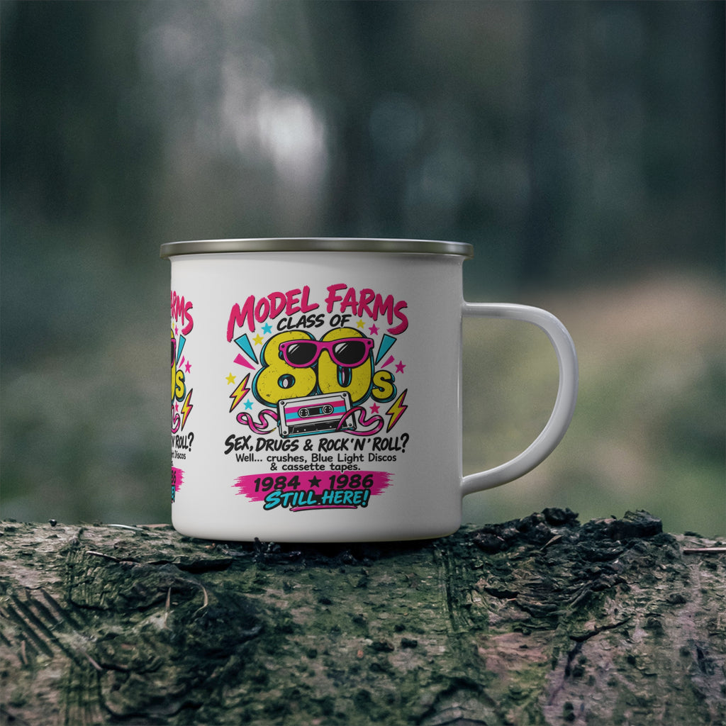 White enamel camping mug with retro cassette graphic on a tree log outdoors