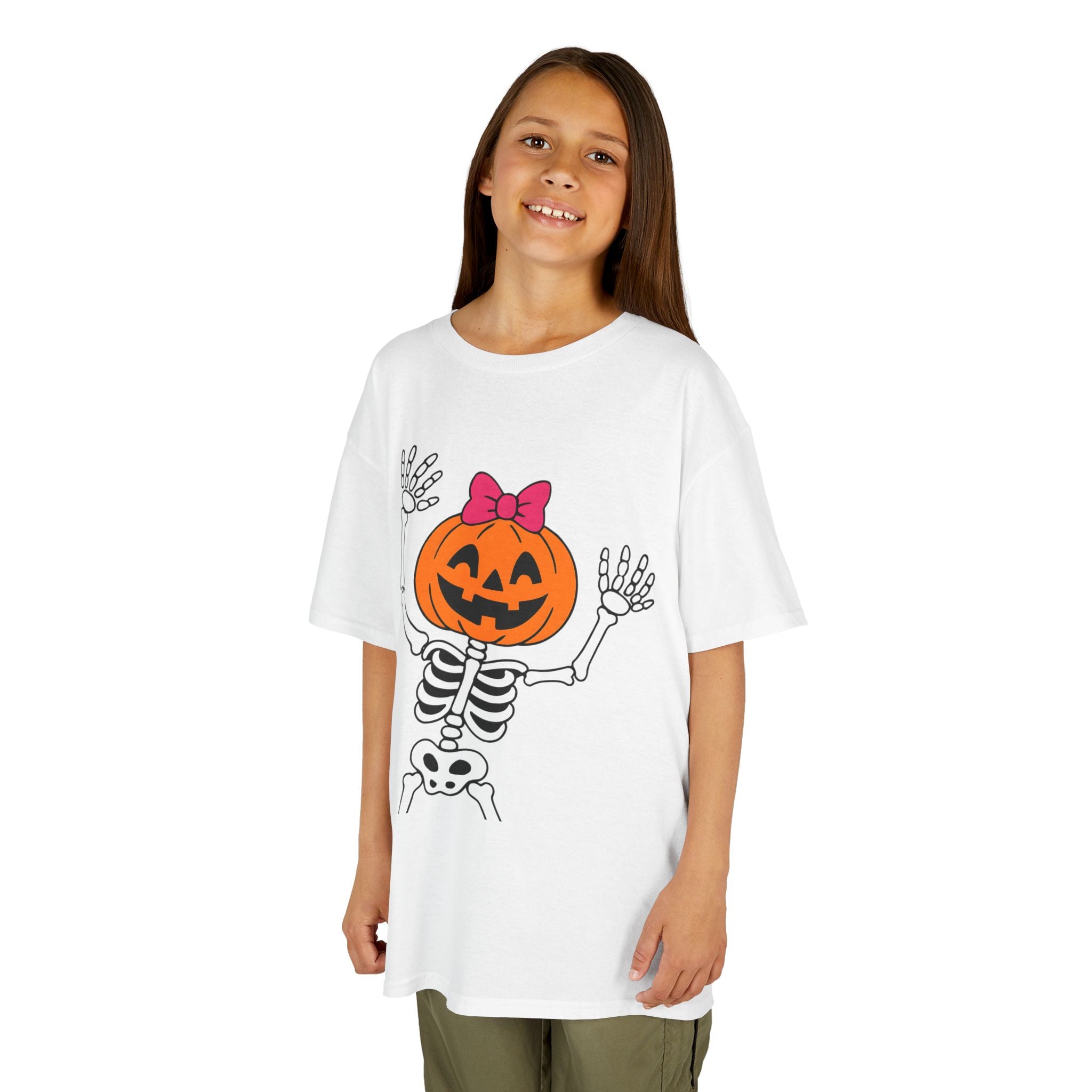 Kids white Halloween tee worn by a child; skeleton jack-o’-lantern pumpkin with pink bow graphic