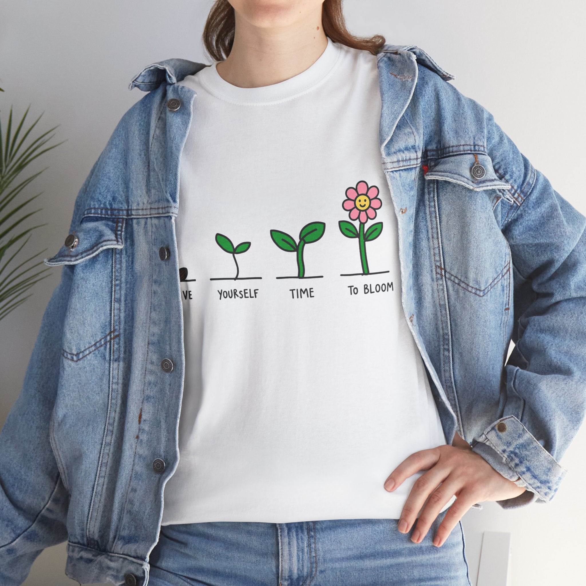 White graphic t-shirt with green growth line and pink flower print, worn by model