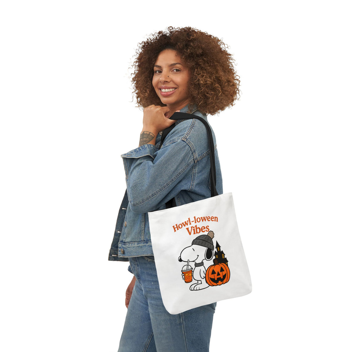 White canvas tote with black handles, worn on shoulder, 'Howl-loween Vibes' print