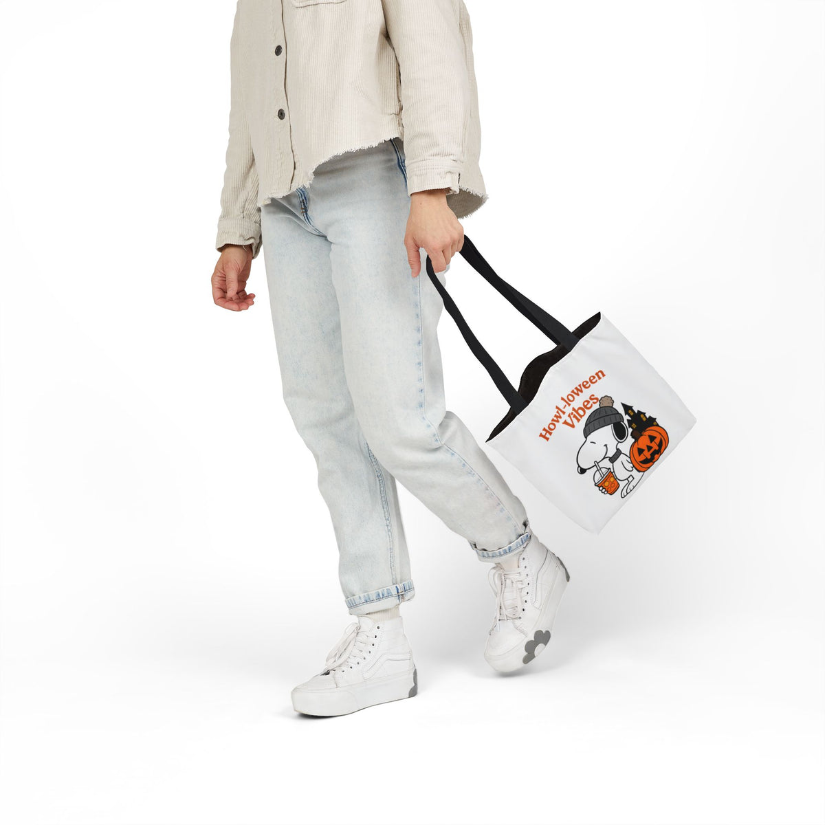 White canvas tote with black handles, held at side, 'Howl-loween Vibes' pumpkin print