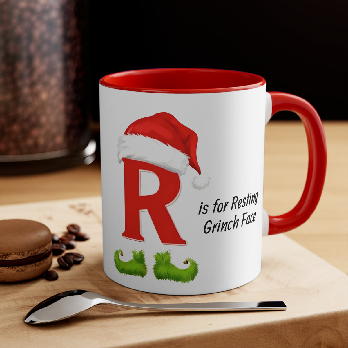 White mug with red handle and rim, red letter R and Grinch face holiday graphic
