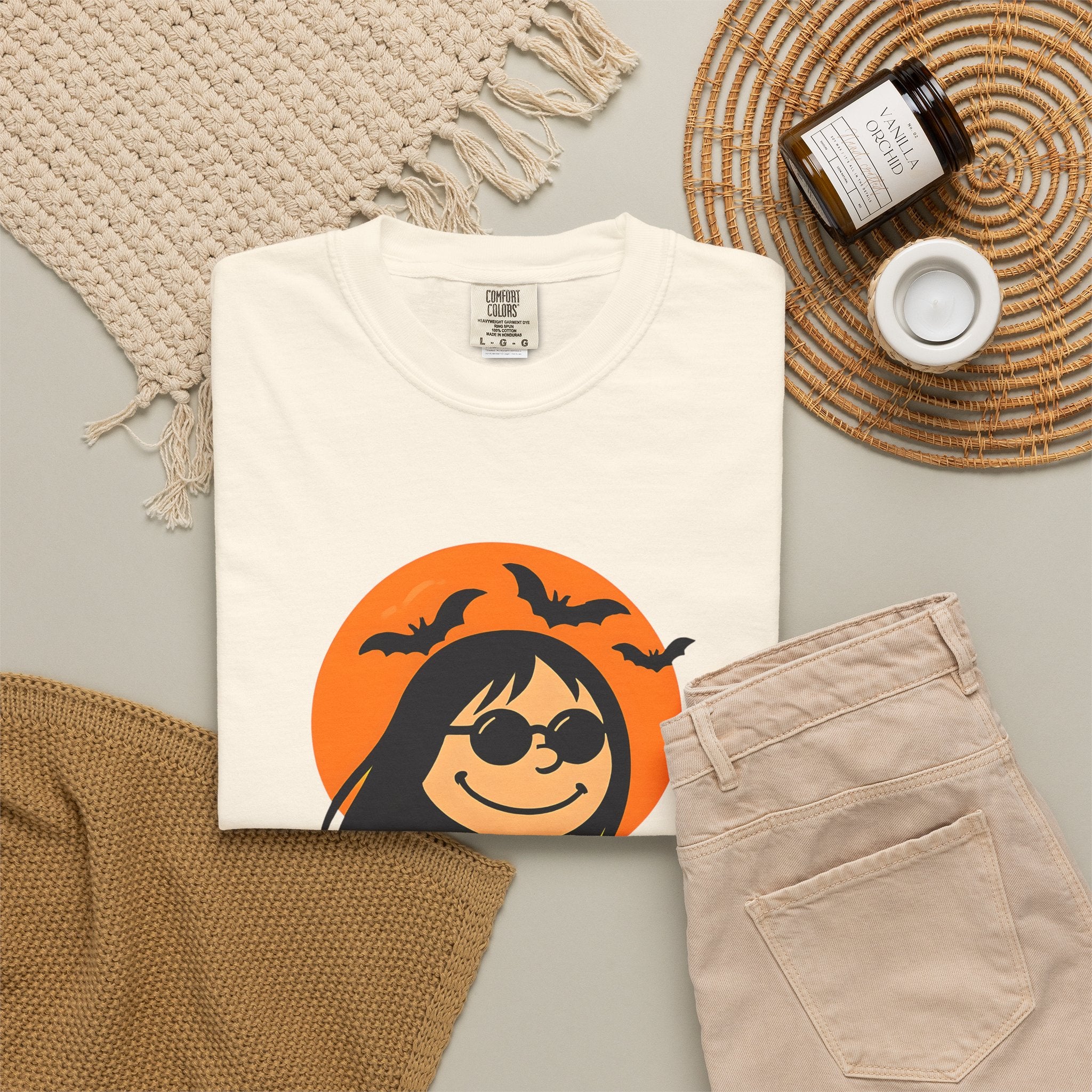 Ivory unisex T-shirt laid flat with orange Halloween witch character graphic