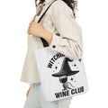 White canvas tote bag with black handles, witch hat and wine club graphic front.