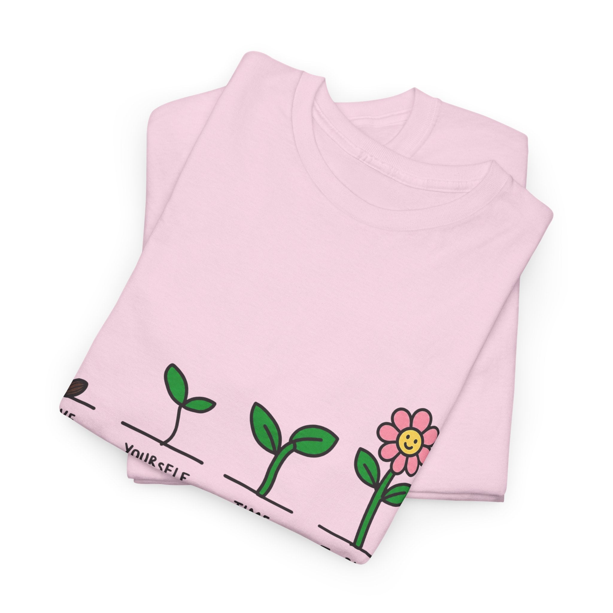 Light pink folded T-shirt with sprout-and-flower growth graphic and message text