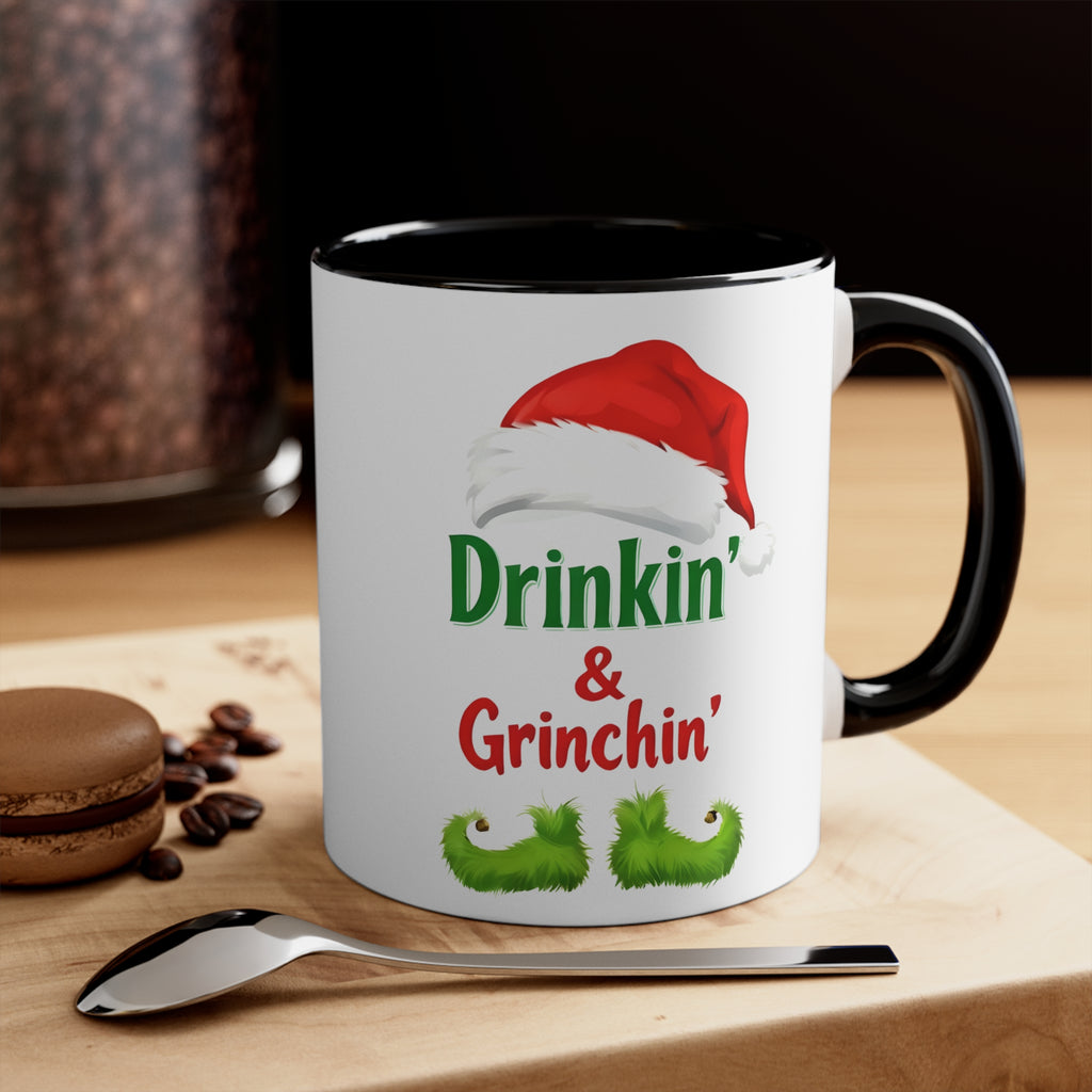 Holiday coffee mug with black handle and rim, white body, 'Drinkin' & Grinchin'' design
