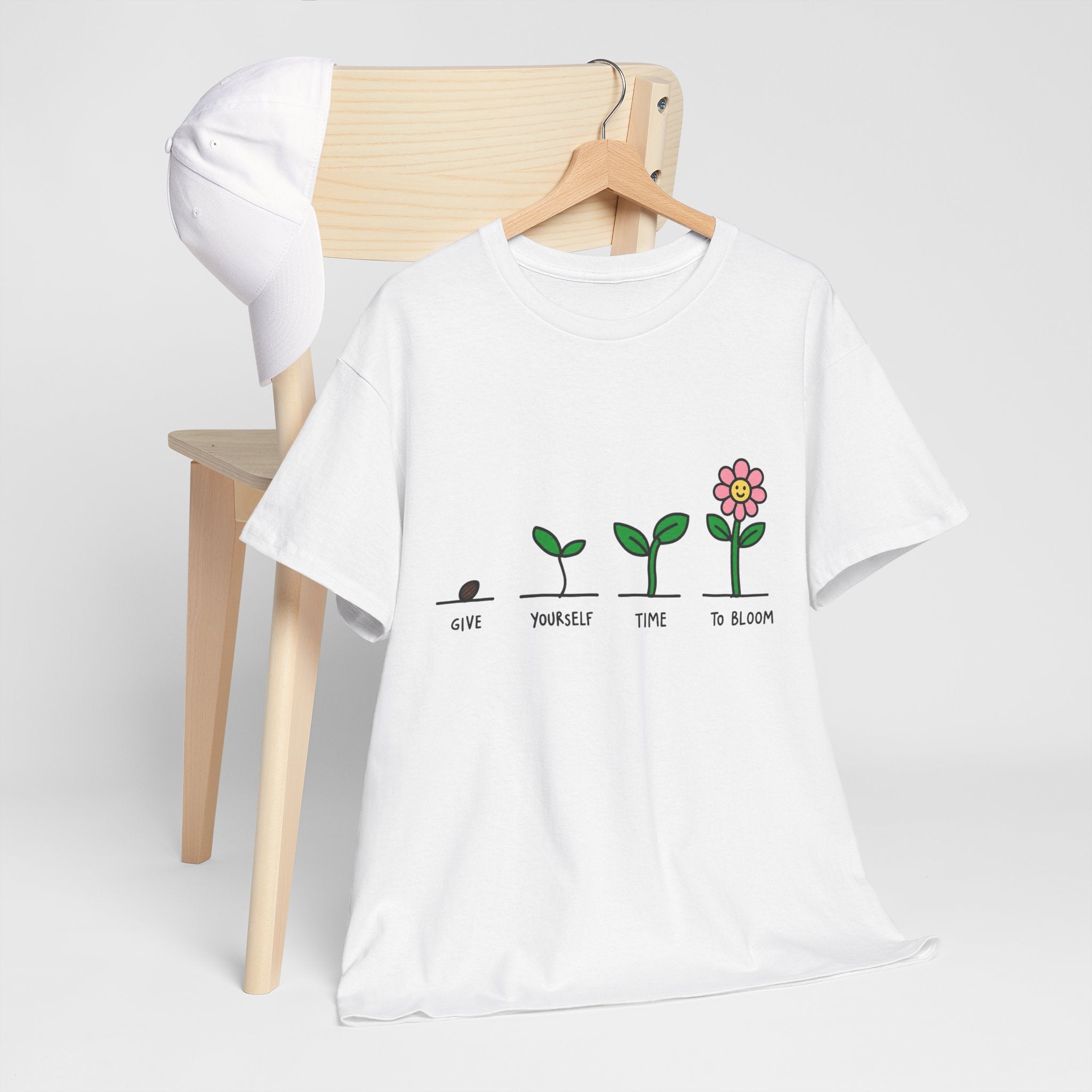 White graphic t-shirt on hanger with green plant growth line and pink flower icon