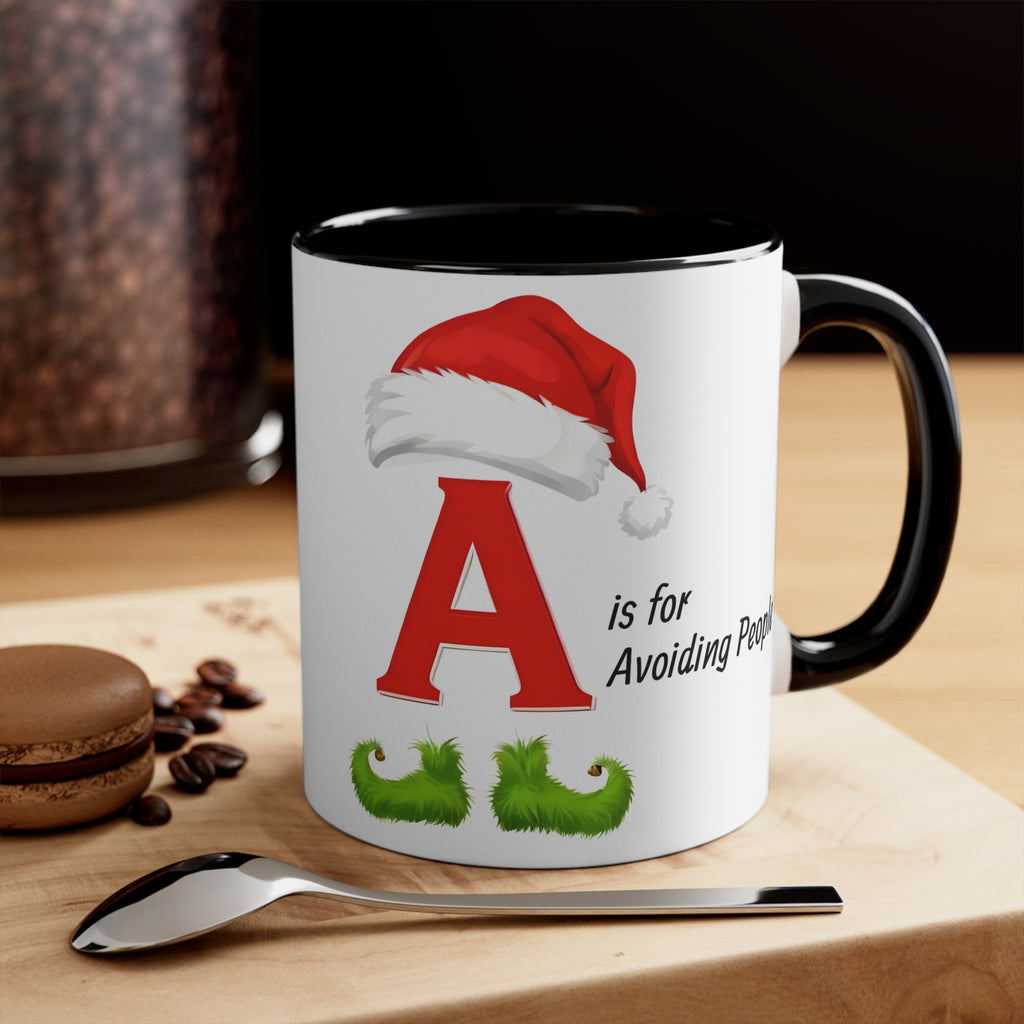 White mug with black handle and black interior; letter A with Santa hat and green mustache text