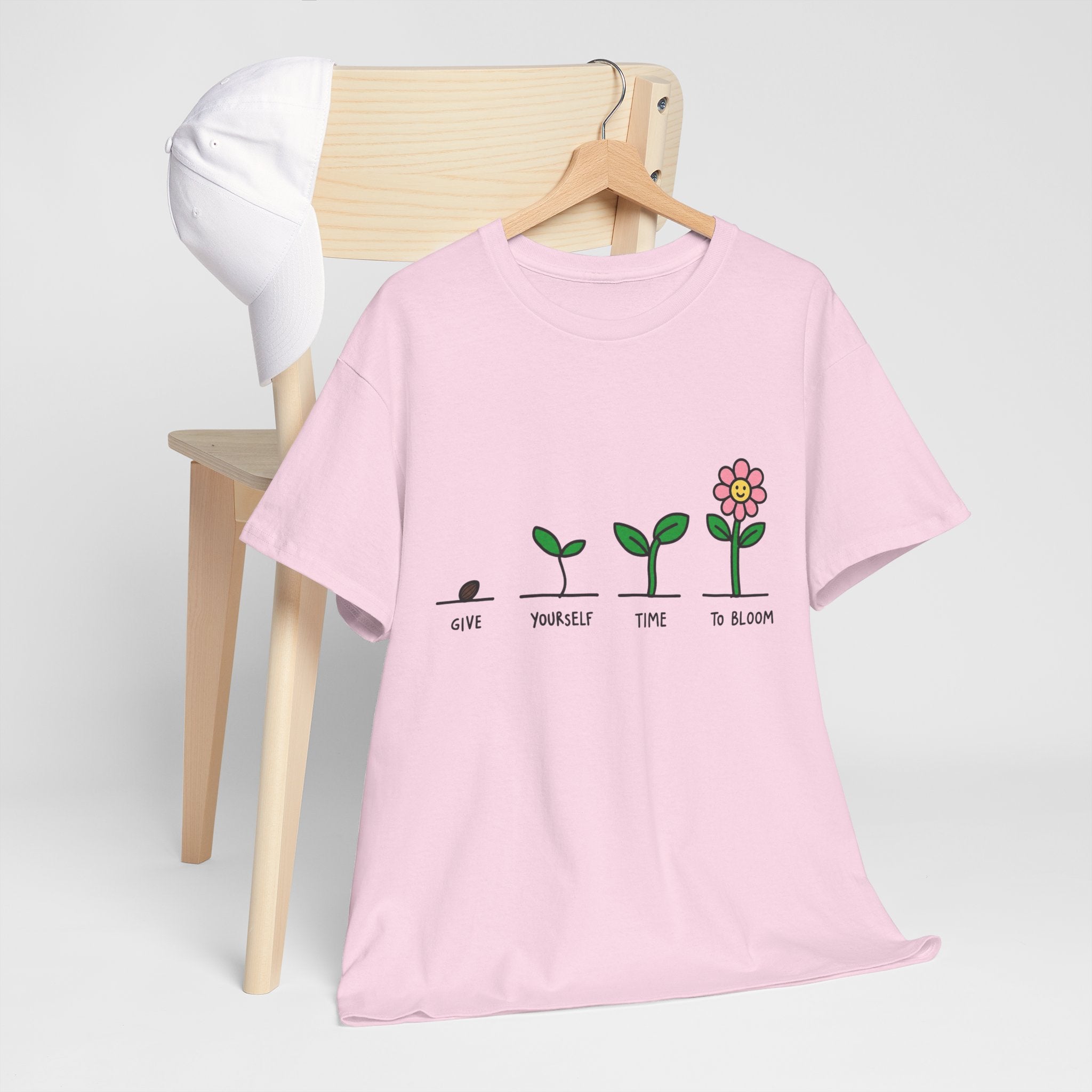 Light pink crew-neck graphic t-shirt on hanger with sprout and flower design