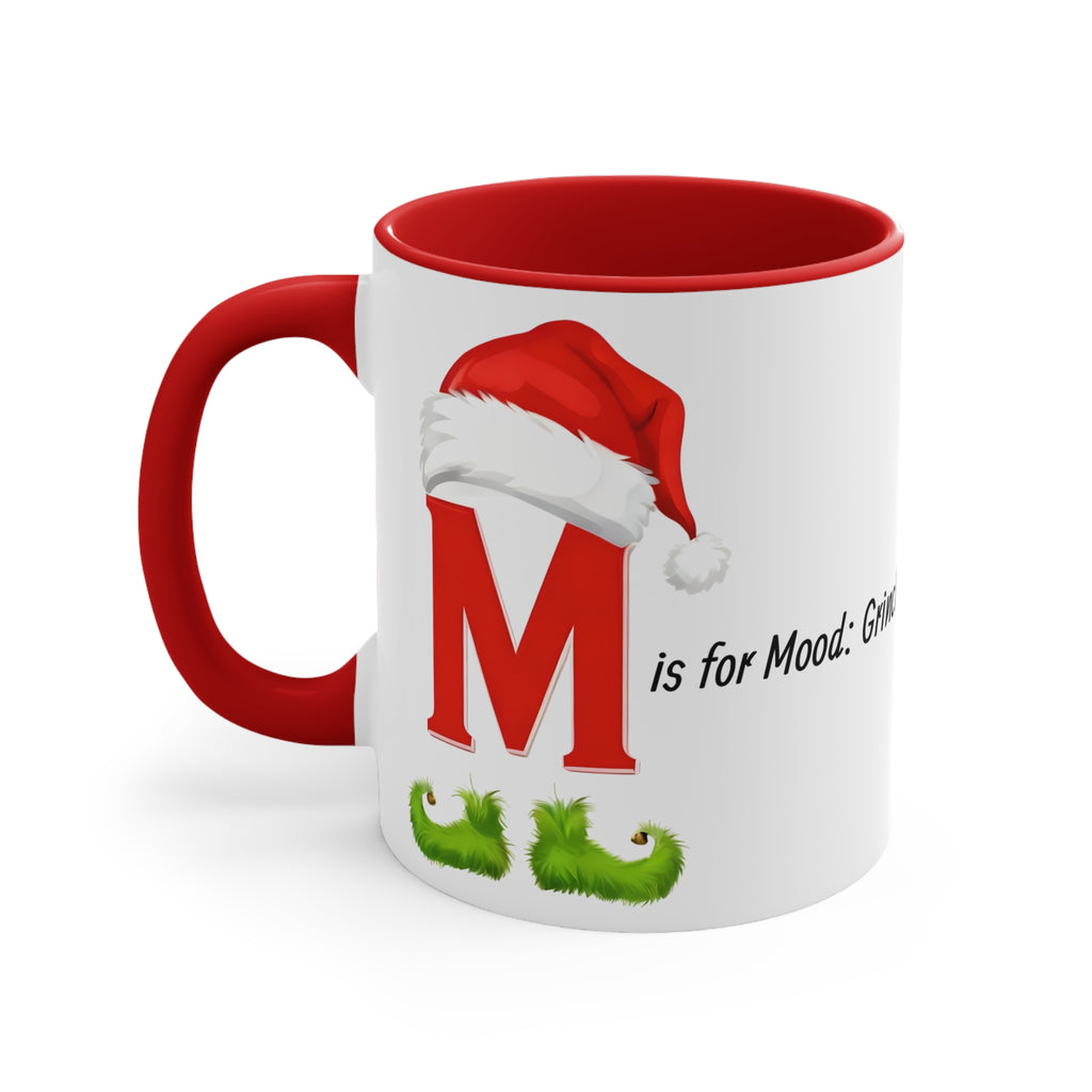 White ceramic letter M mug with red interior and handle; red Santa hat and green feet