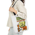 Canvas tote bag with black handles, white body, and colorful Krabby Patties & candy corn print