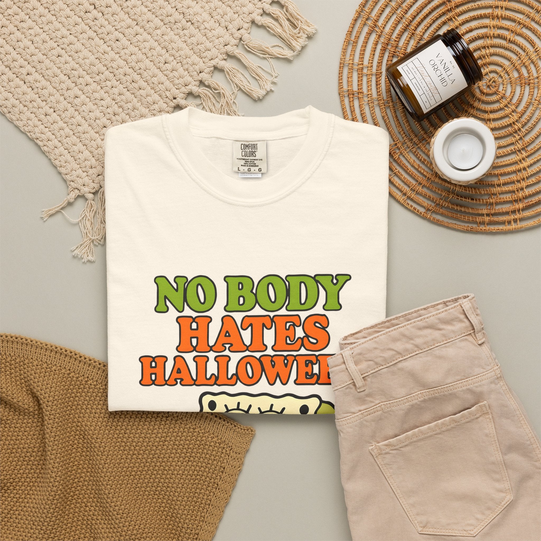 Ivory graphic T-shirt with “NO BODY HATES HALLOWEEN” sponge text and pumpkin illustration