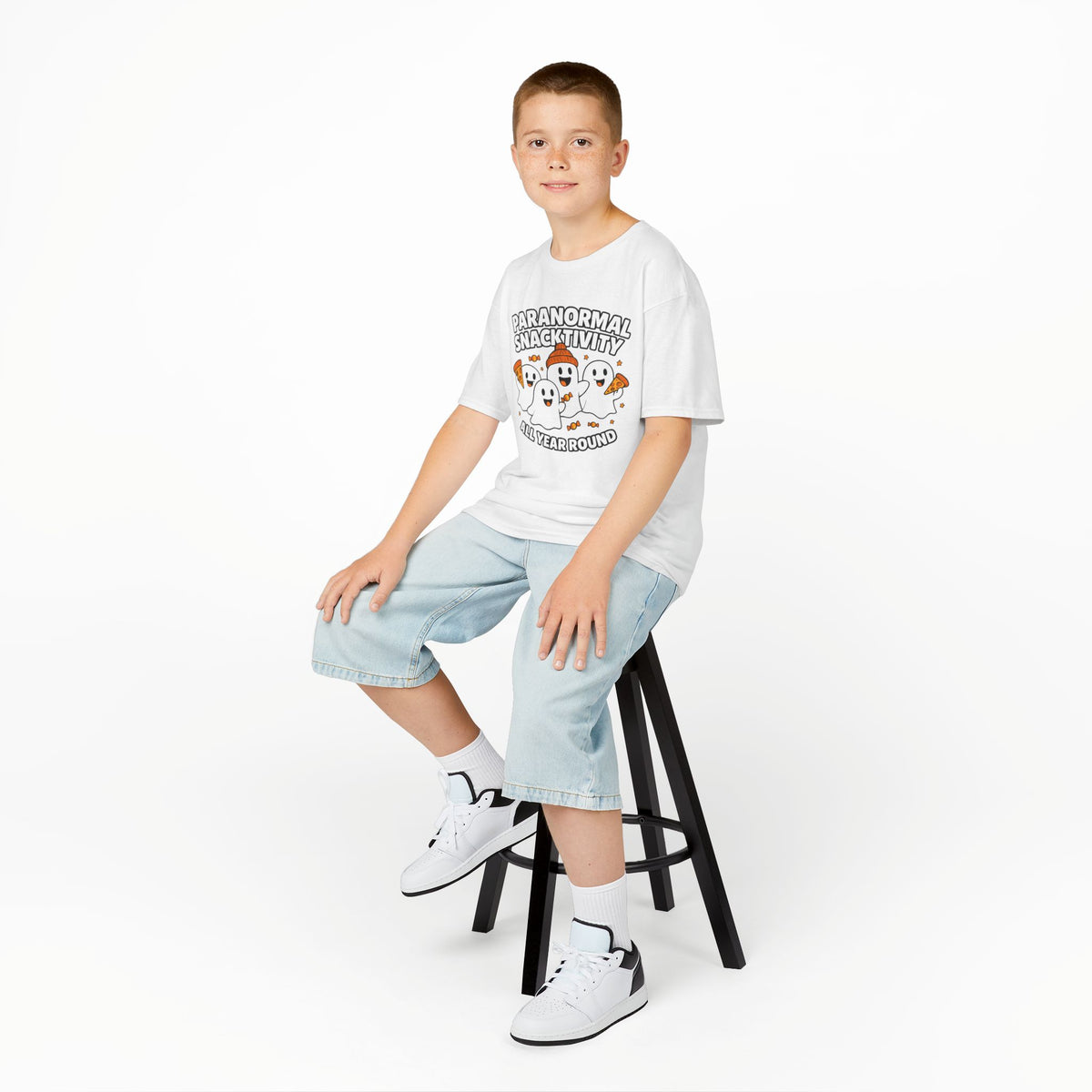 Kids white T-shirt with cute ghost cartoon graphic, worn with denim shorts and sneakers
