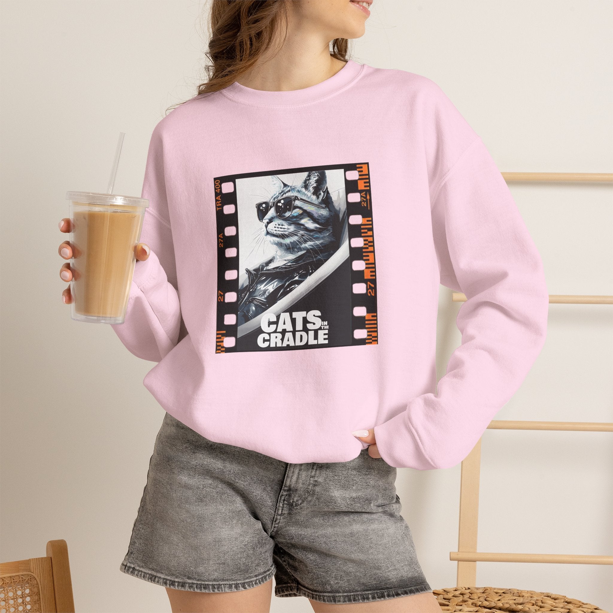 Light pink crewneck sweatshirt on model with cat filmstrip graphic on chest