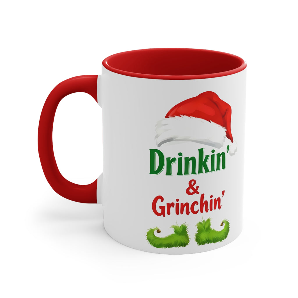 Holiday coffee mug with red handle and rim; front-facing Drinkin' & Grinchin' design.