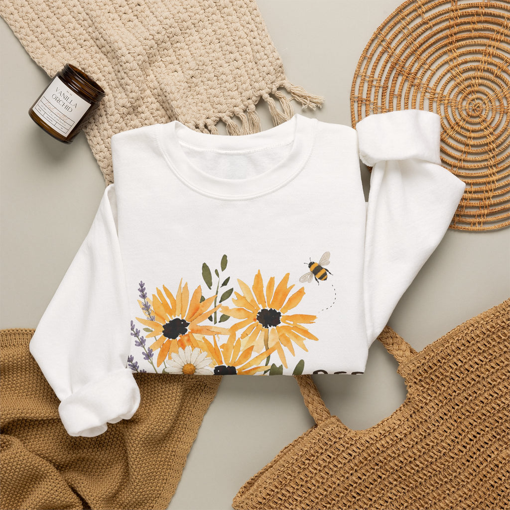 White crewneck sweatshirt with sunflower bouquet print and bee; partial 'BEE Kind'.
