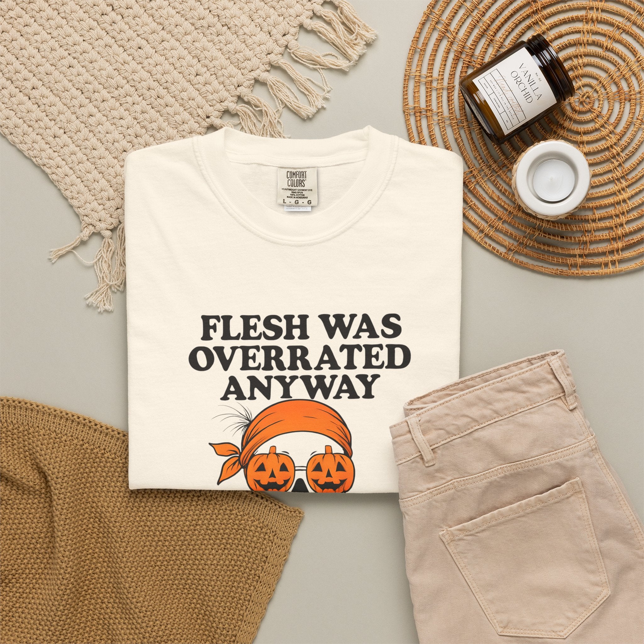 Ivory Halloween graphic unisex tee shown folded, with orange jack-o-lantern skull print