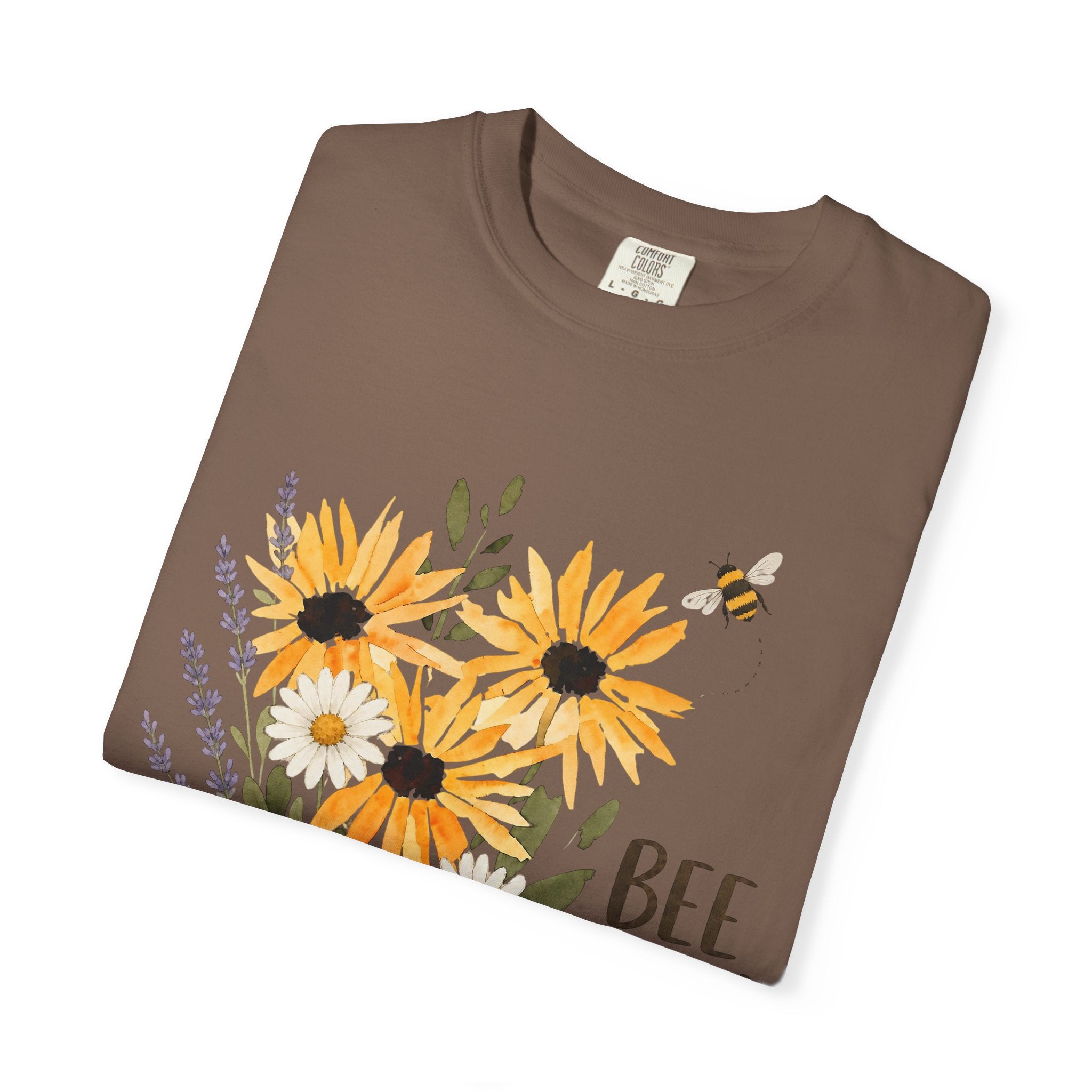 Brown t-shirt close-up with sunflower and lavender bouquet graphic and 'Bee Kind' text