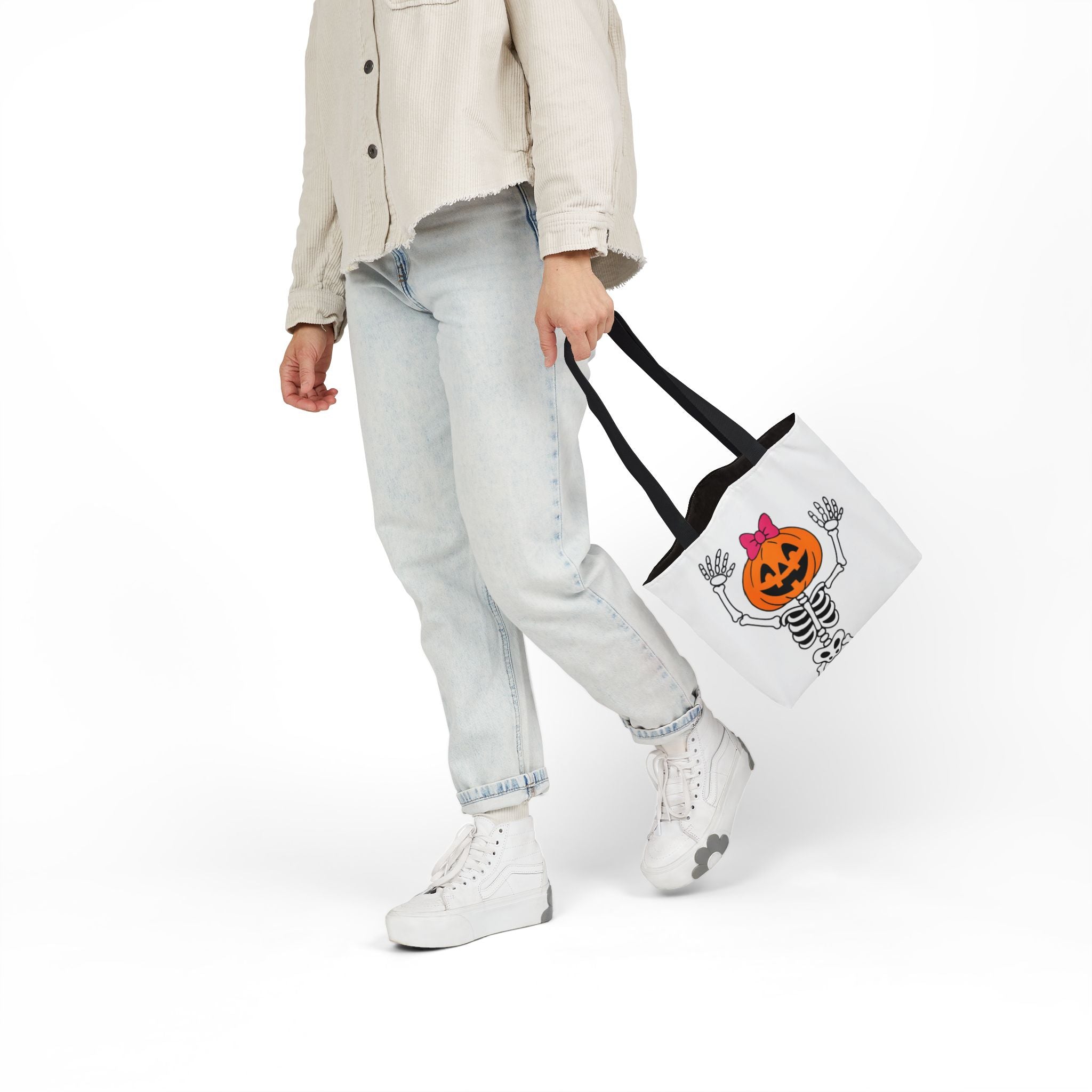 White canvas tote bag with black handles, side view with pumpkin skeleton hands-up print