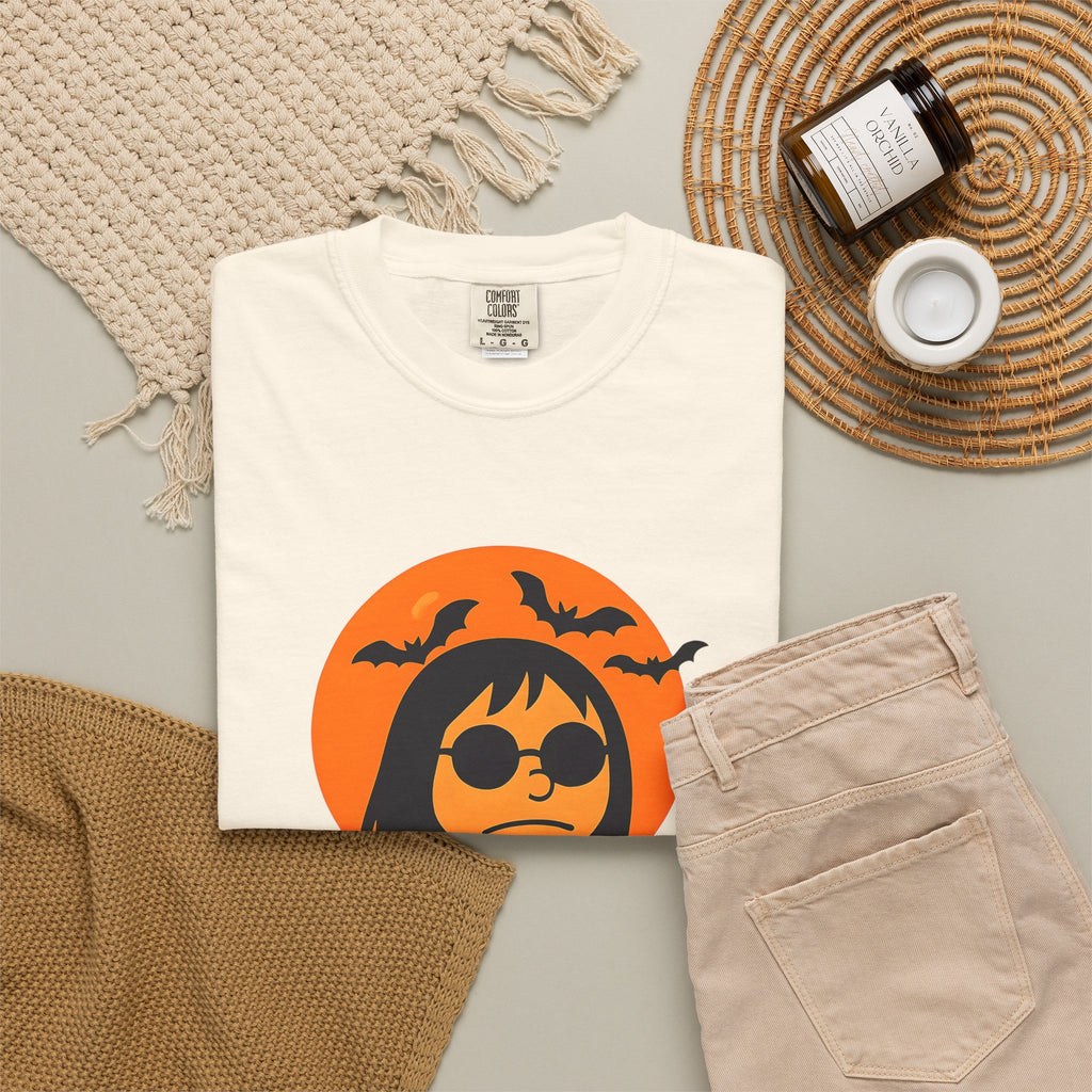 Ivory unisex T-shirt folded, orange Halloween character graphic with “Madman Miles”