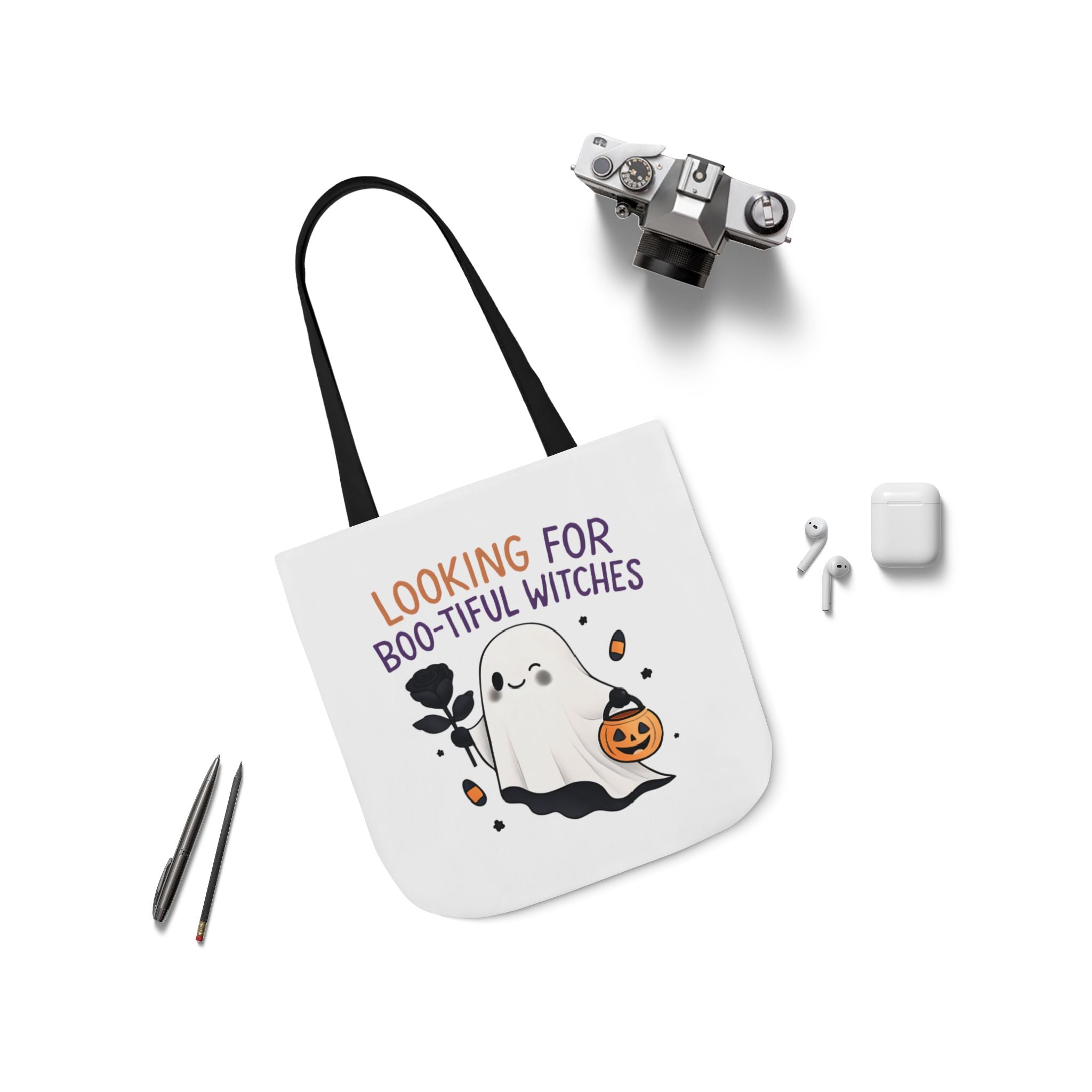 Flat-lay white canvas tote bag with black handles; ghost and pumpkin front design