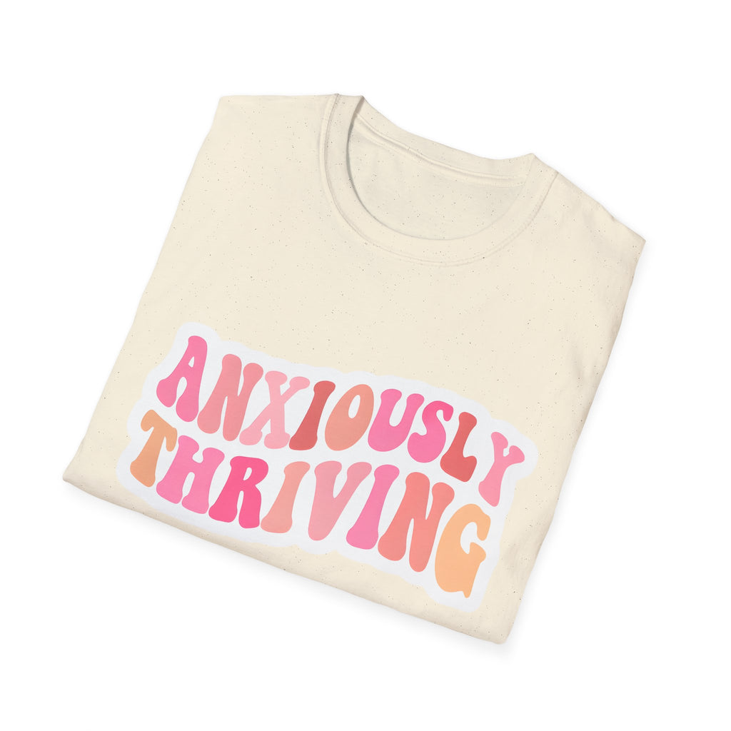 Unisex T-shirt laid flat in natural/off-white with 'ANXIOUSLY THRIVING' chest print
