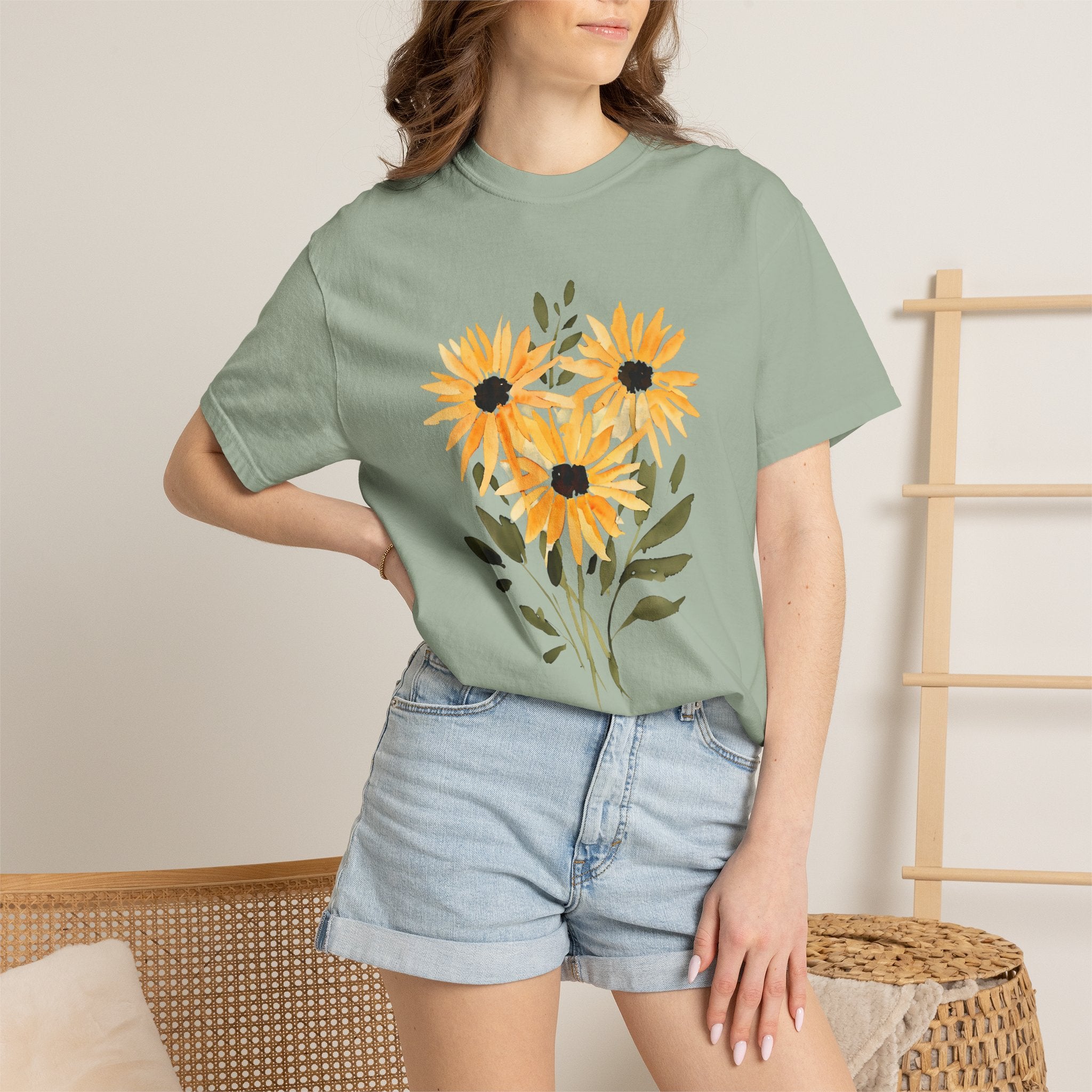 Sage green t-shirt with sunflower bouquet graphic in orange and black at the chest