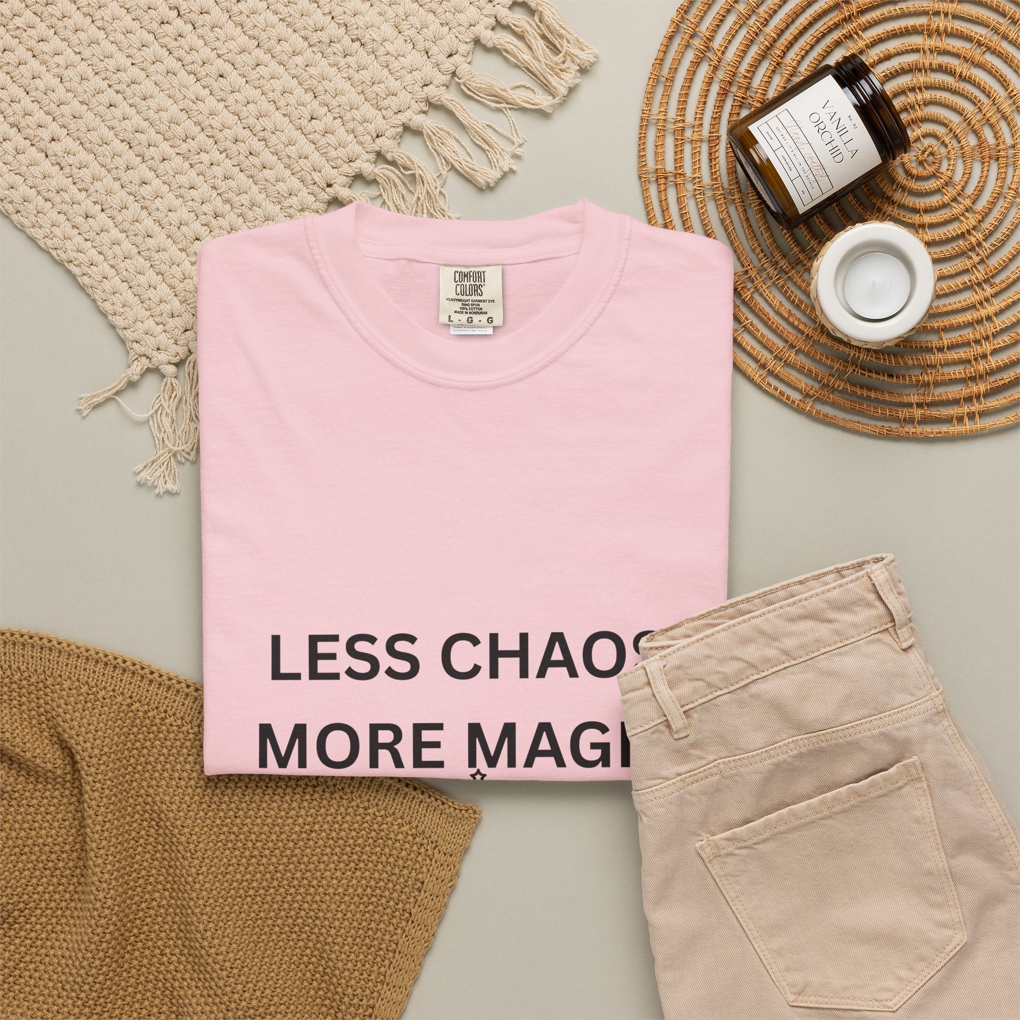 Pink crewneck T-shirt with “Less Chaos, More Magic” text graphic at the hem