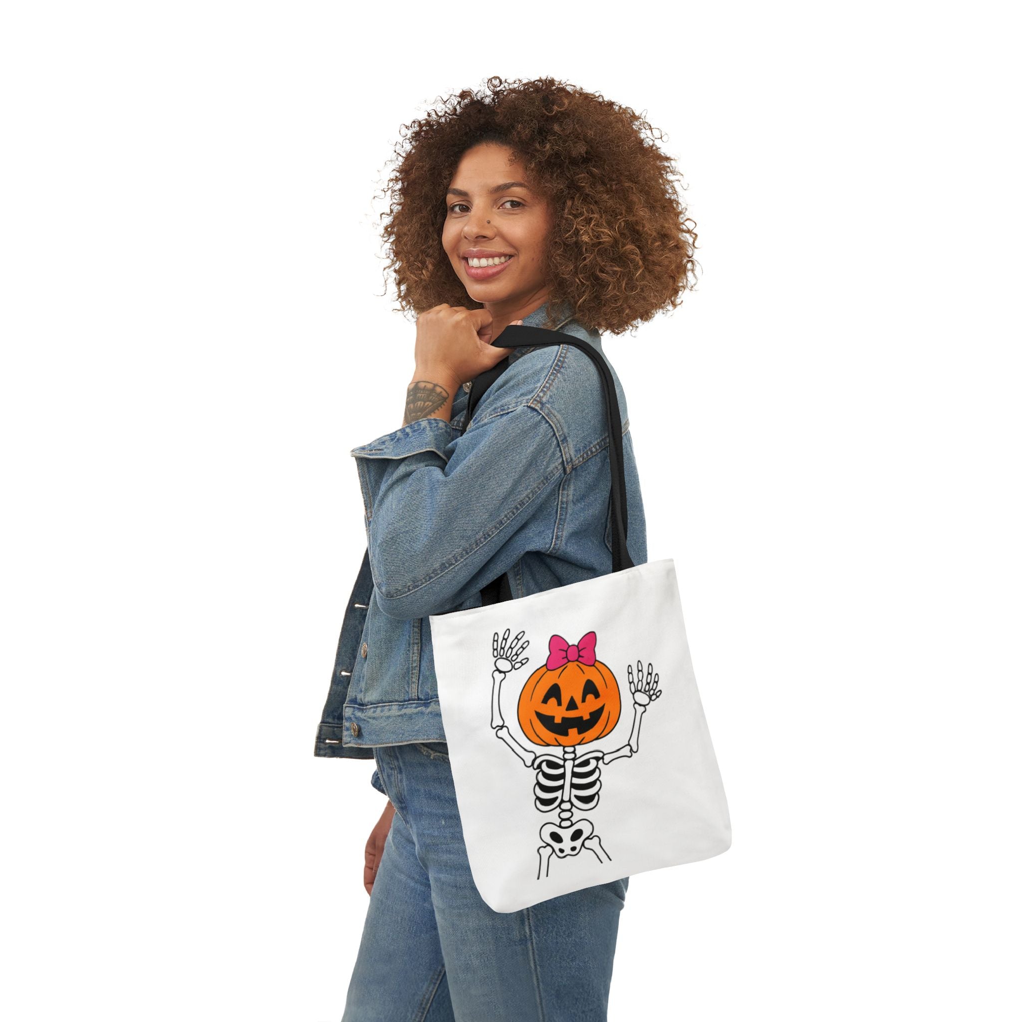 White canvas tote bag with black handles, pumpkin skeleton graphic shown on model