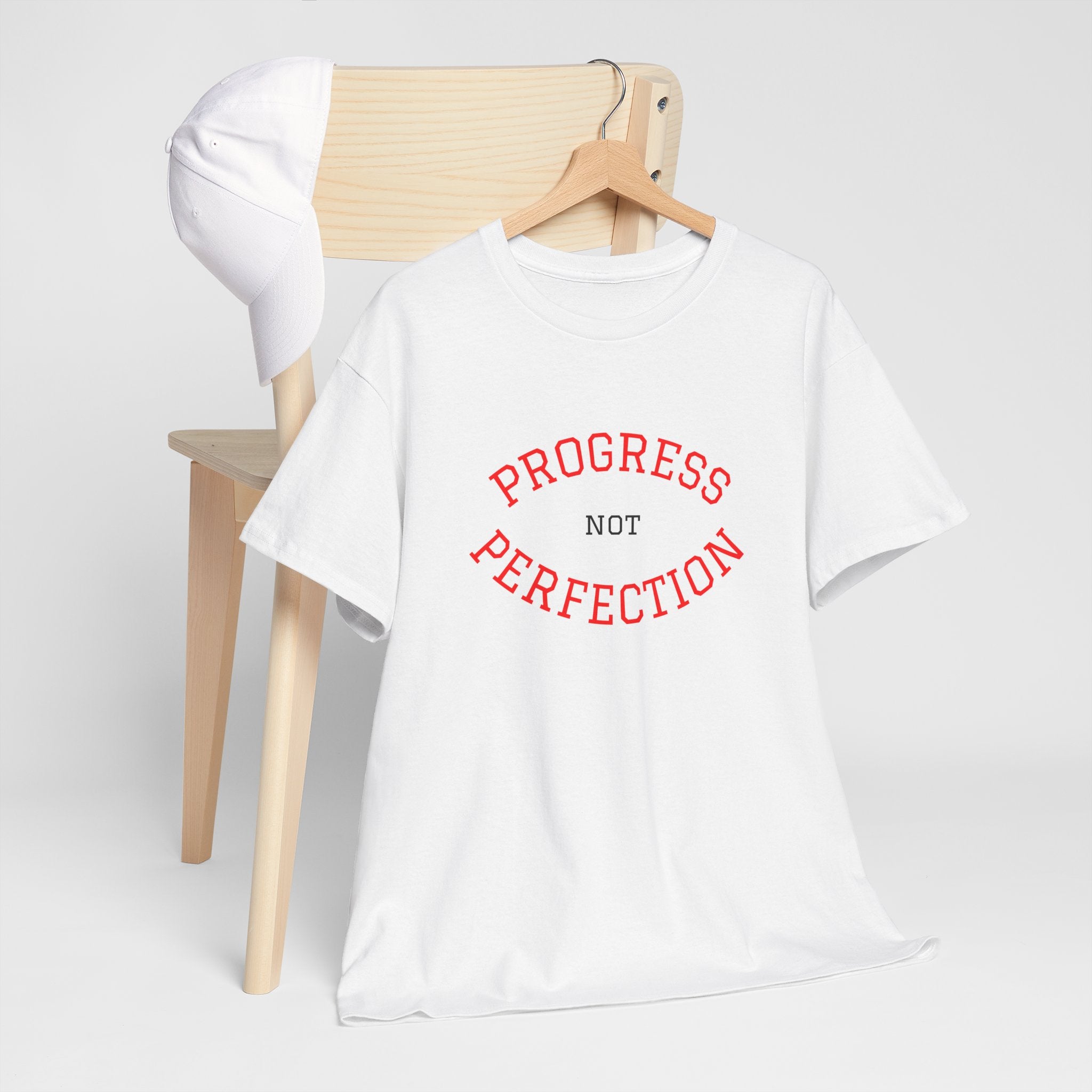 White unisex cotton tee on hanger with red "PROGRESS NOT PERFECTION" slogan
