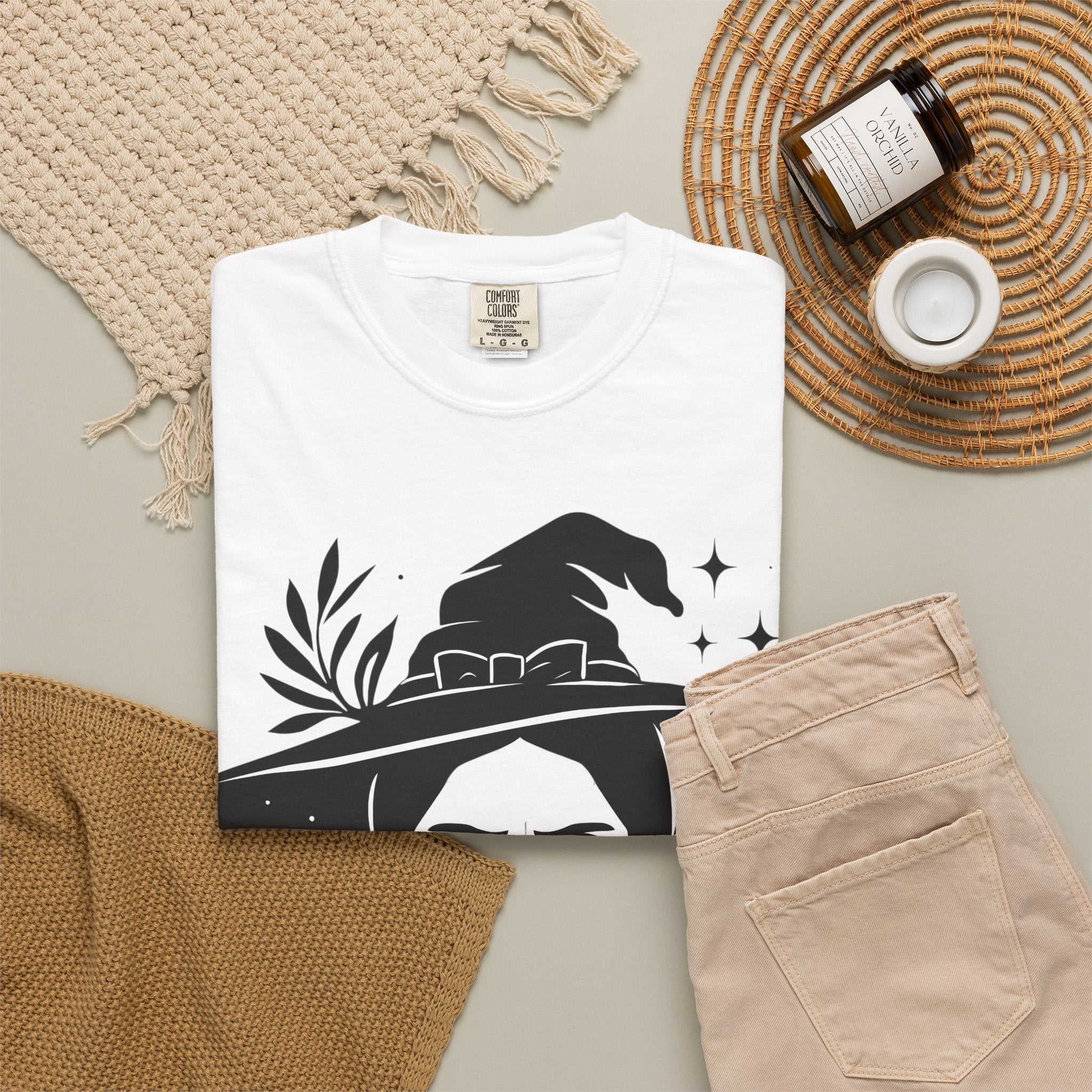 White witch graphic T-shirt with black hat portrait, folded with accessories
