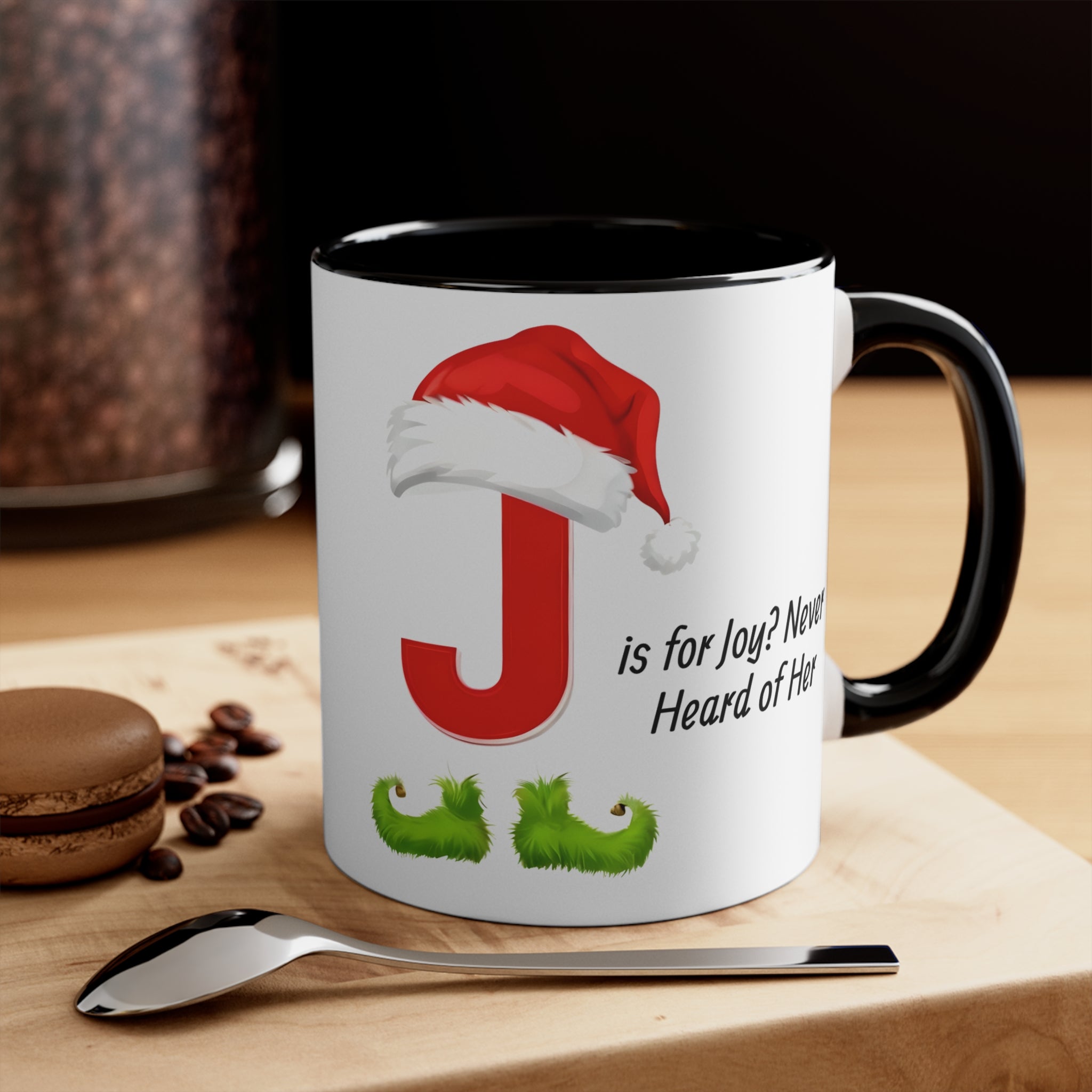 White mug with black handle and interior, red letter J with Santa hat and green boots