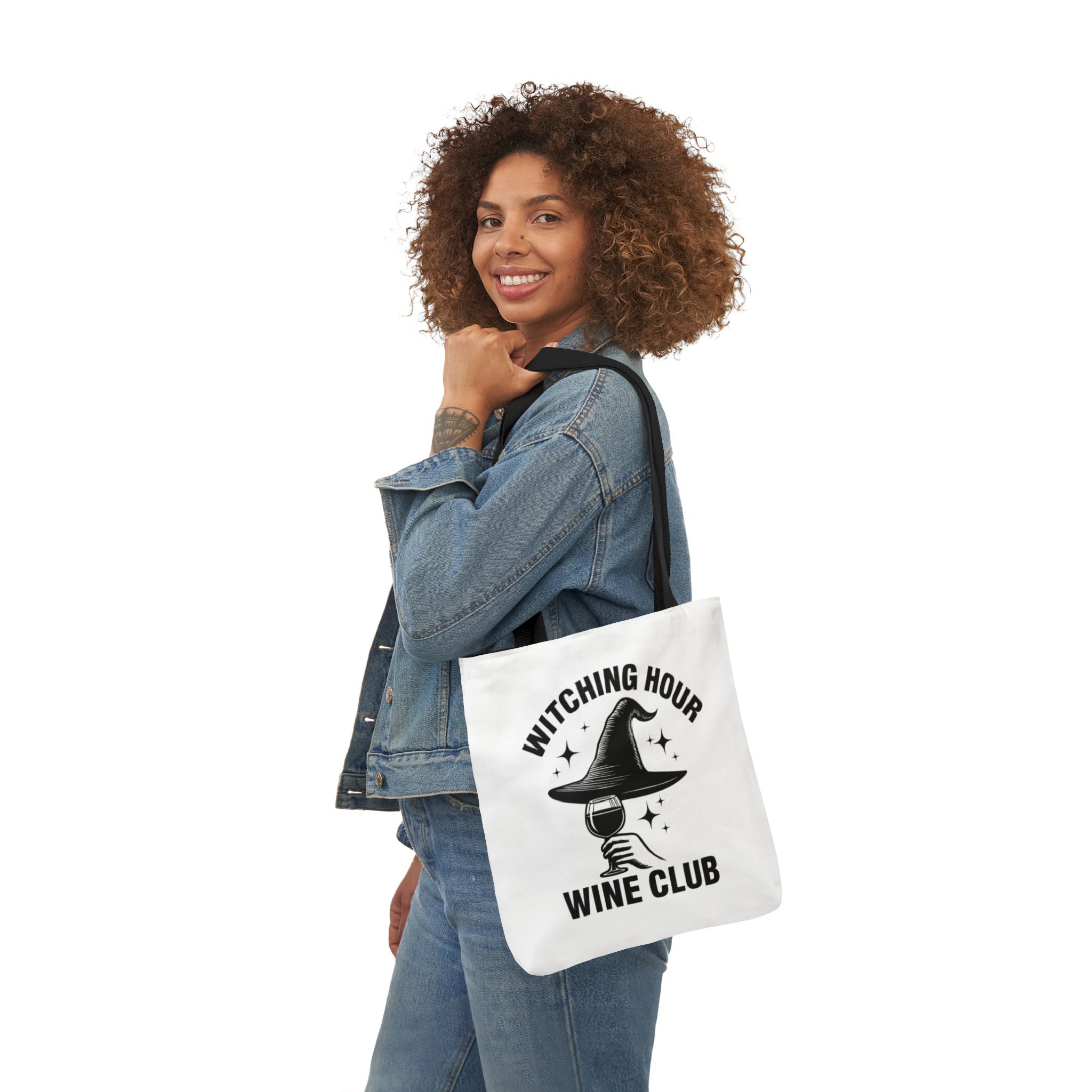 White canvas tote bag with black handles, witching hour wine club print while carried.