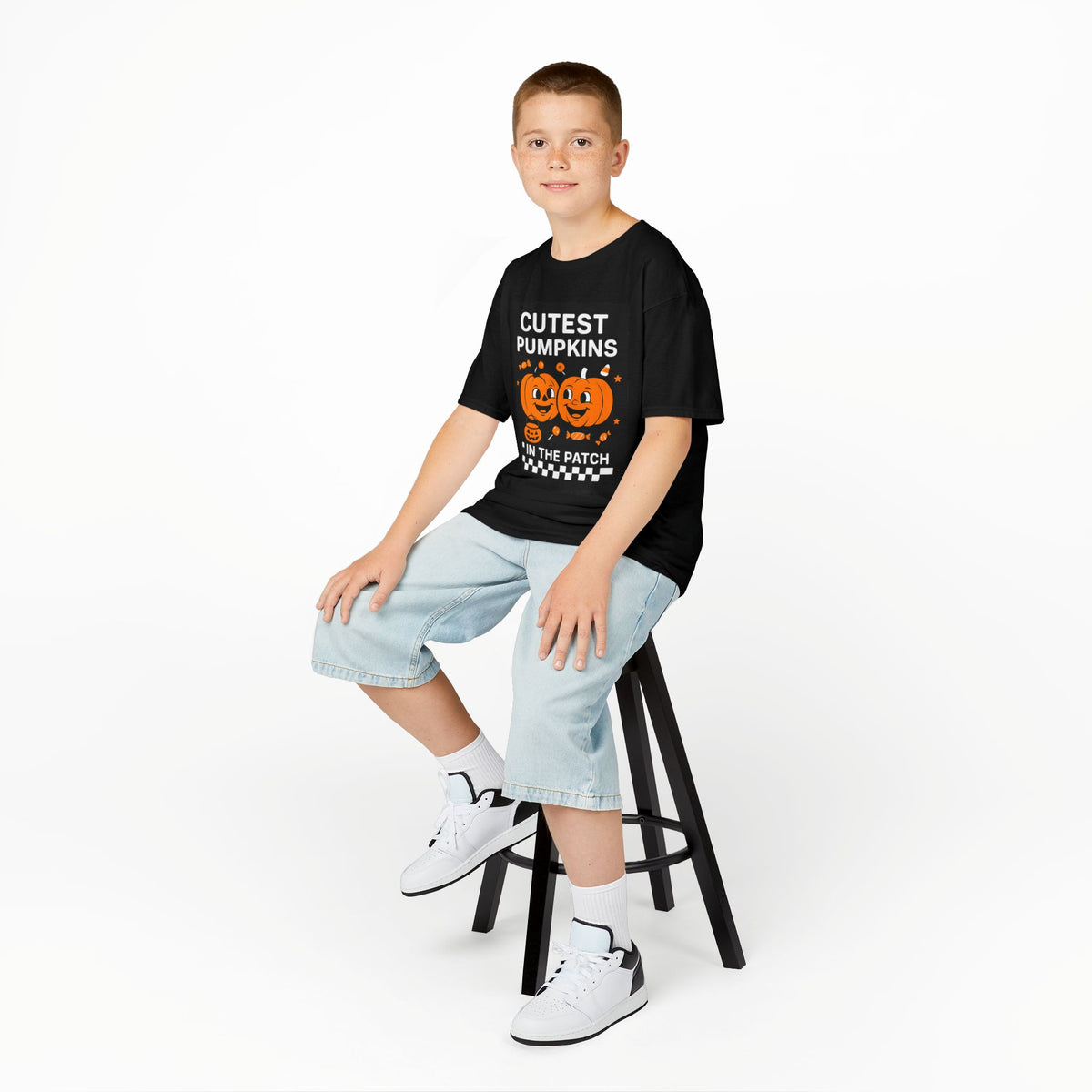Kids black Halloween tee with pumpkin graphic front, styled with denim shorts and sneakers