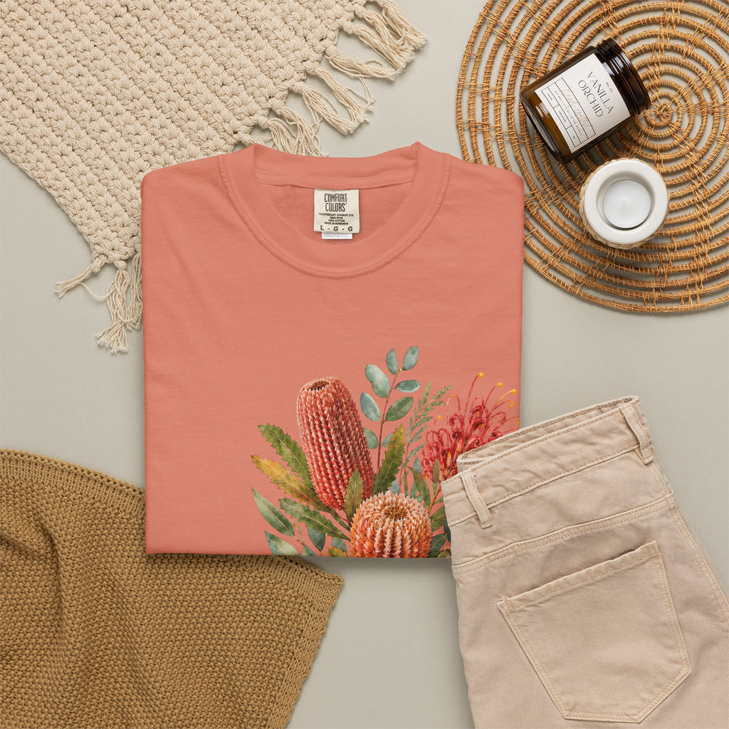Terracotta crew-neck t-shirt with colorful protea bouquet graphic, styled flat-lay