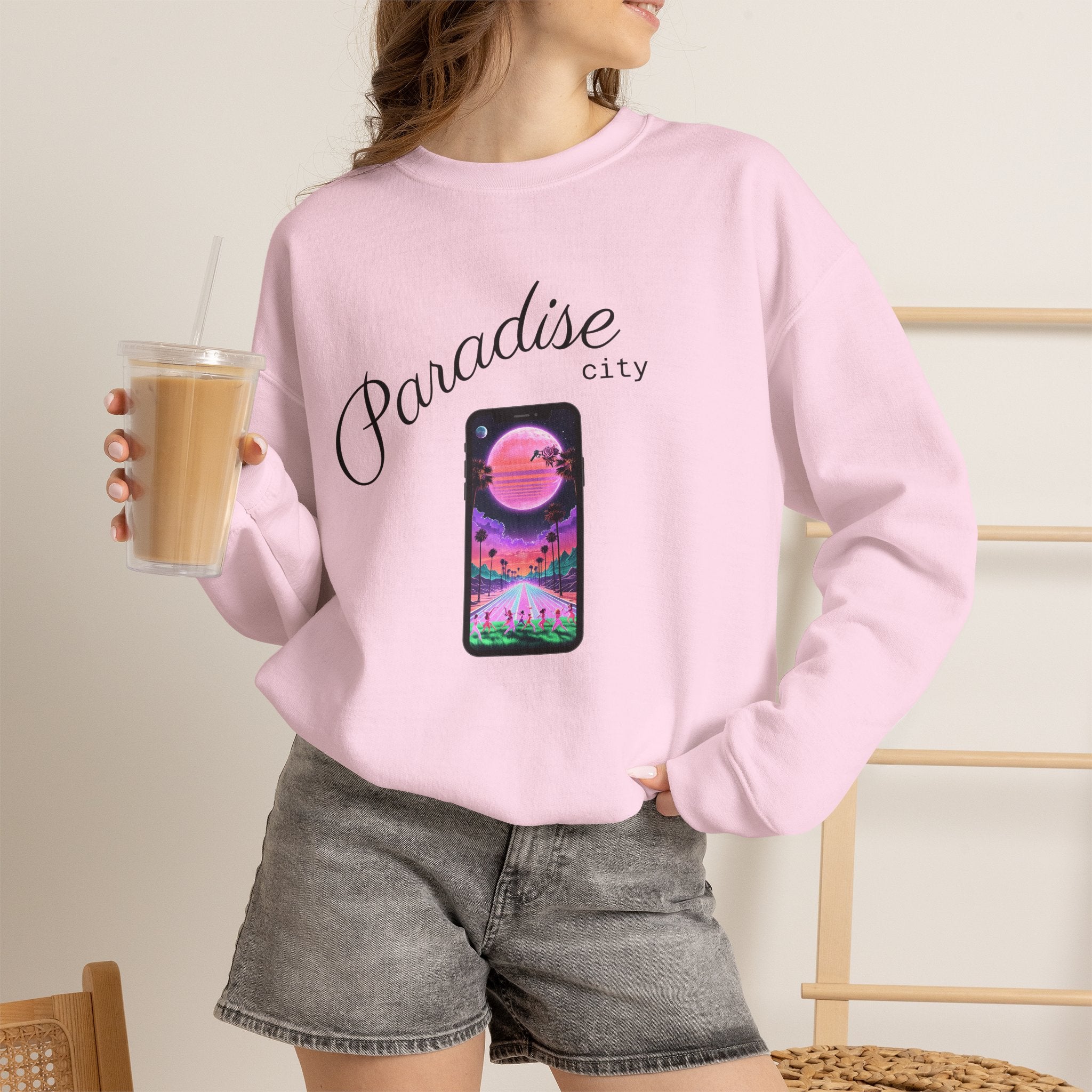 Light pink crewneck sweatshirt worn by model with phone graphic and city text